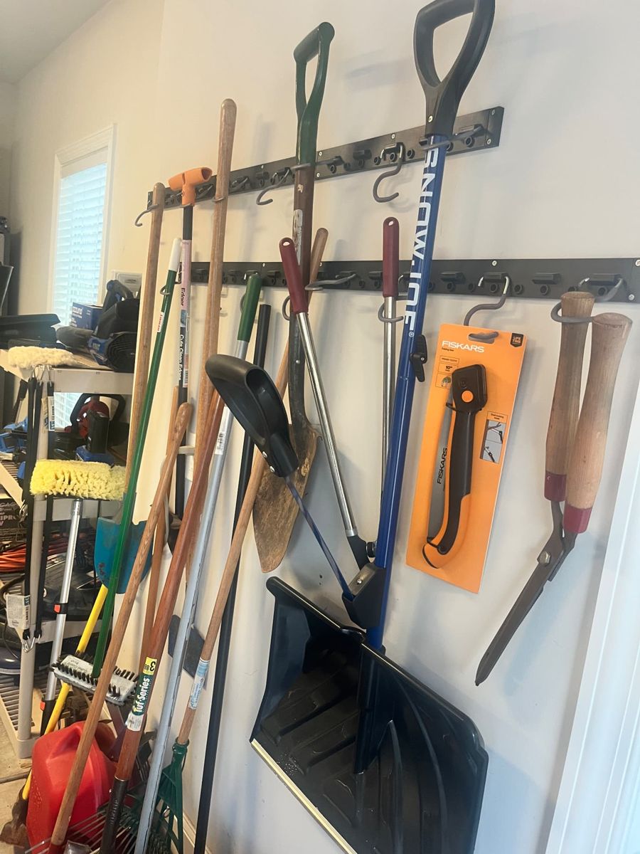 Before: rakes, shovels, and yard tools stored on a wall rack