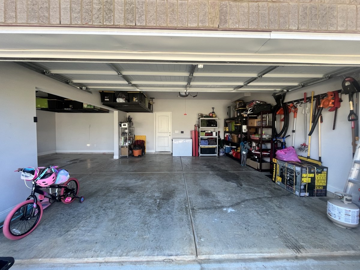After: the same garage with a clear floor, items on shelving and wall racks, and overhead storage
