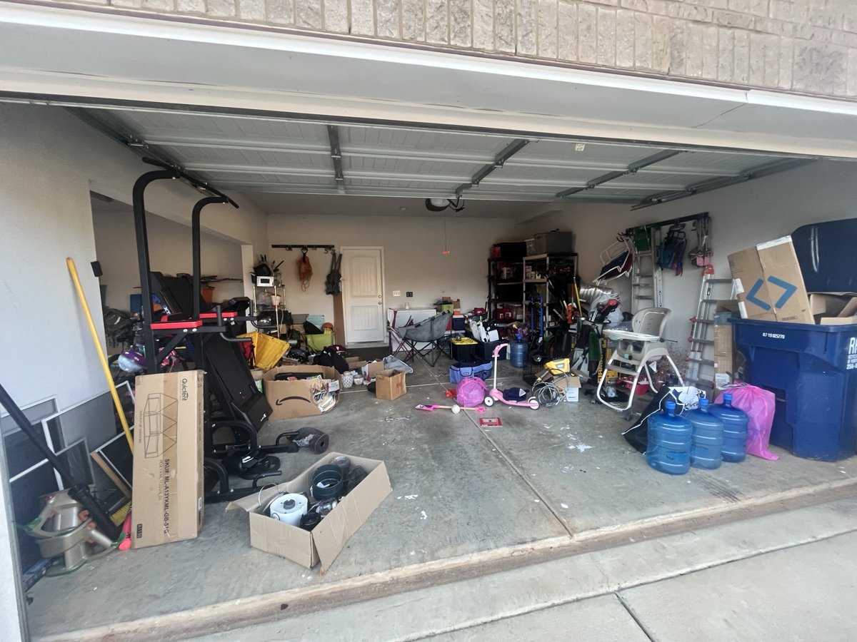 Before: two-car garage crowded with boxes, exercise equipment, toys, and loose items covering the floor