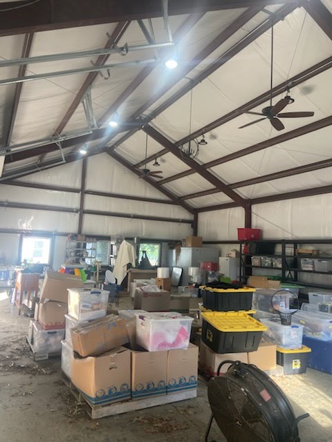 Before: shop with boxes, bins, and belongings stacked across much of the floor