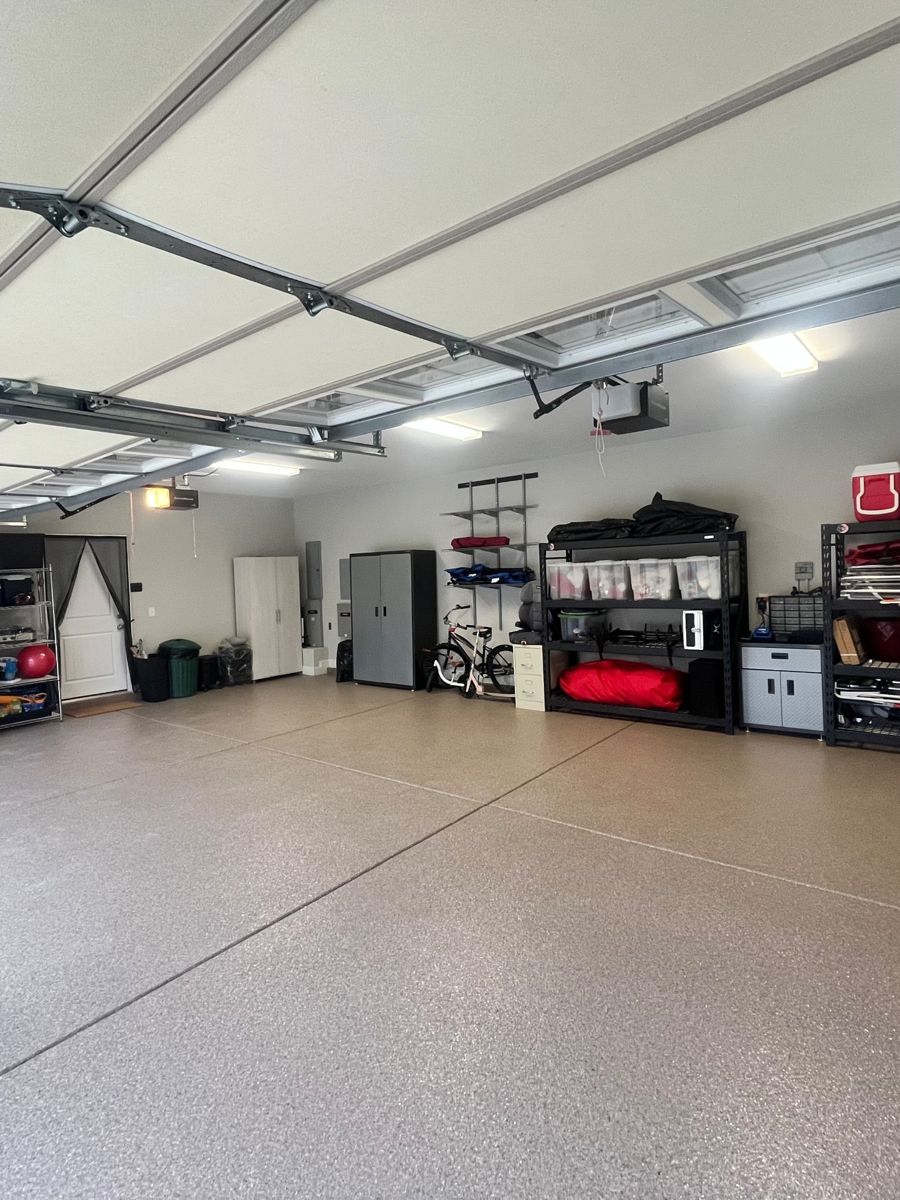 After: the same garage with a speckled epoxy floor, shelving with bins along the walls, and open floor space