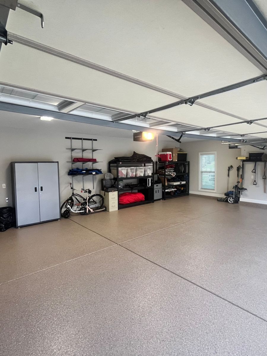 After: finished garage with cabinets, shelving, a bike, and a speckled epoxy floor