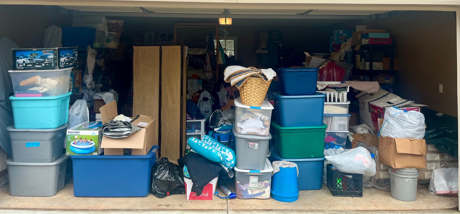 Before: garage completely filled with stacked storage bins, boxes, bags, and belongings