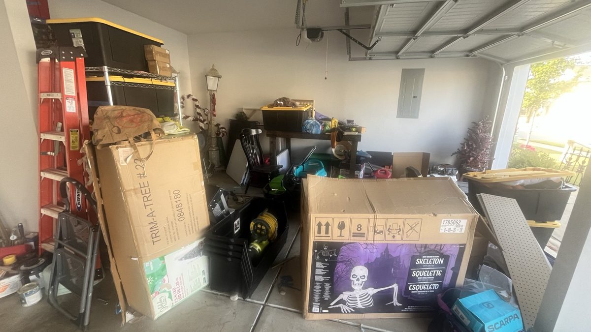 Before: garage packed with large holiday decoration boxes, bins, a ladder, and loose items across the floor