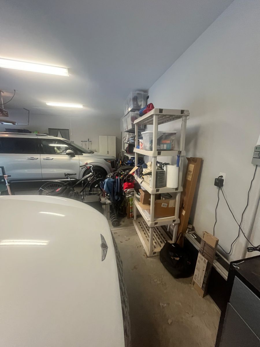 Before: side of the garage with a car, shelving, and stored items along the wall