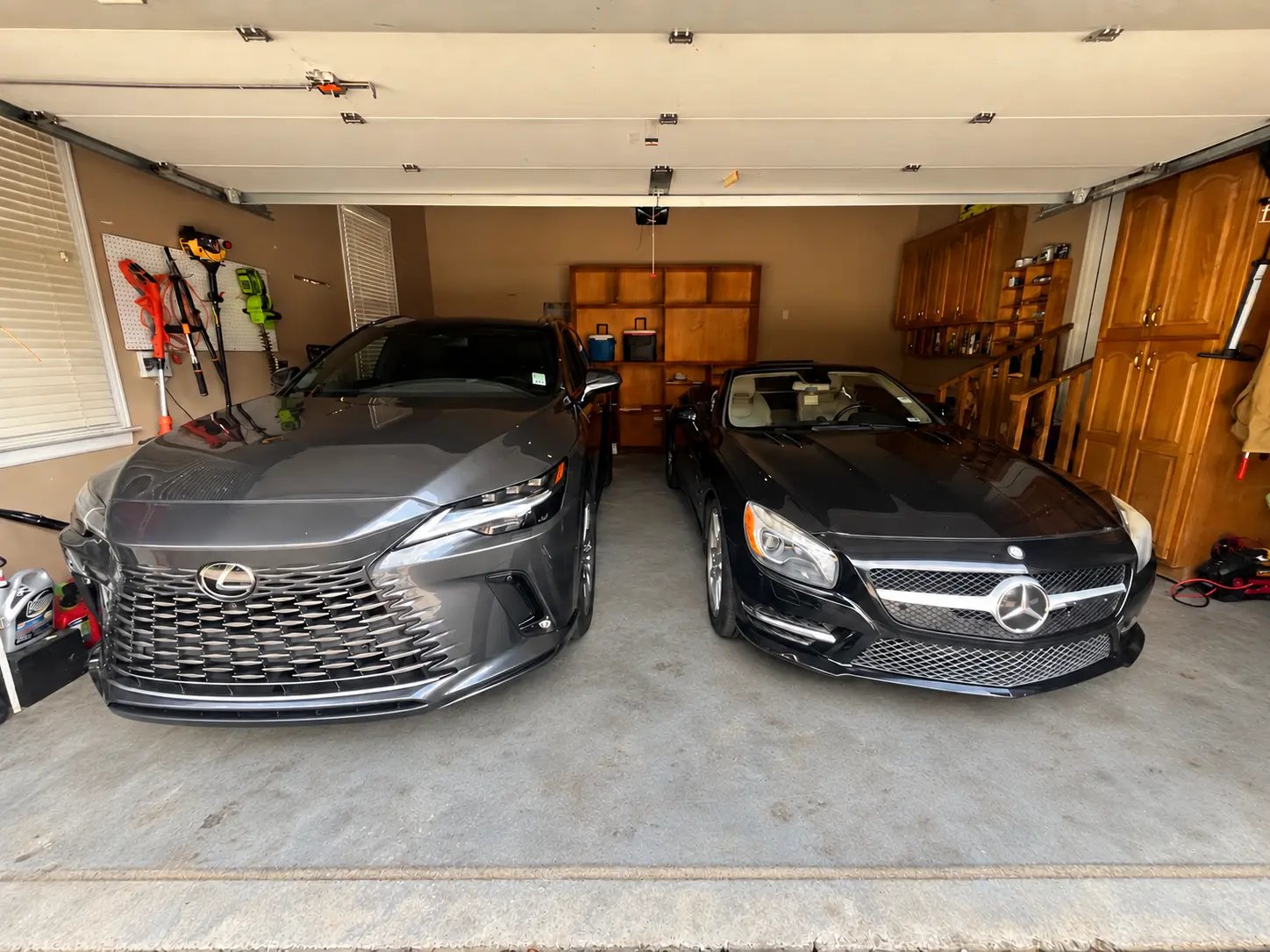 After: the same garage with two cars parked inside, a clear floor, and tools hung on the pegboard wall